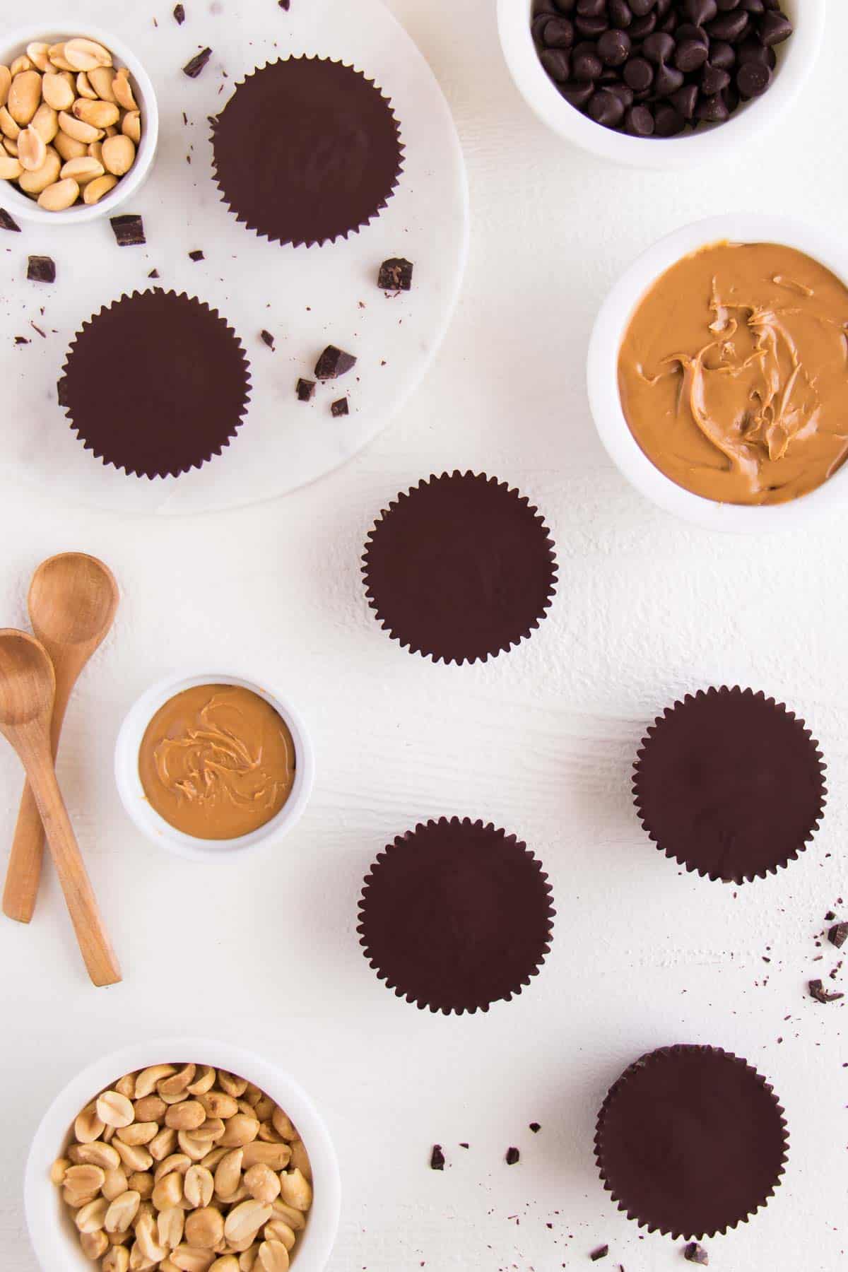 dark chocolate discs surrounded by wooden spoons, crushed nuts, and nut butter