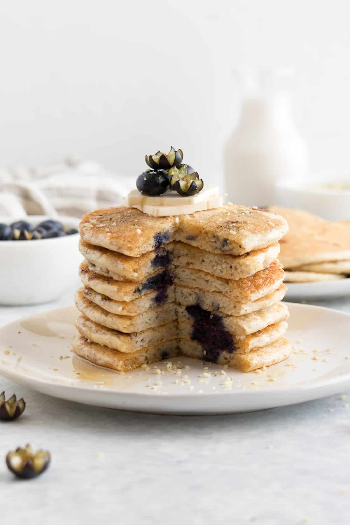 a sliced stack of fluffy pancakes with blueberries and butter