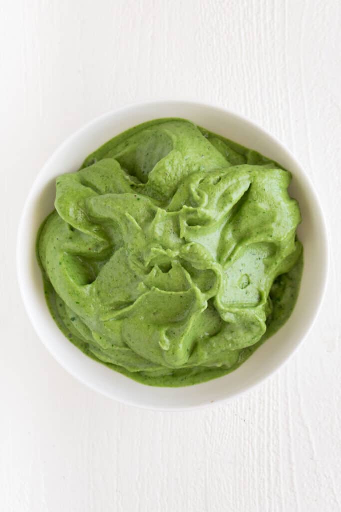 a thick green smoothie poured into a white dish