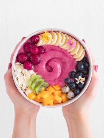 two hands holding a smoothie bowl