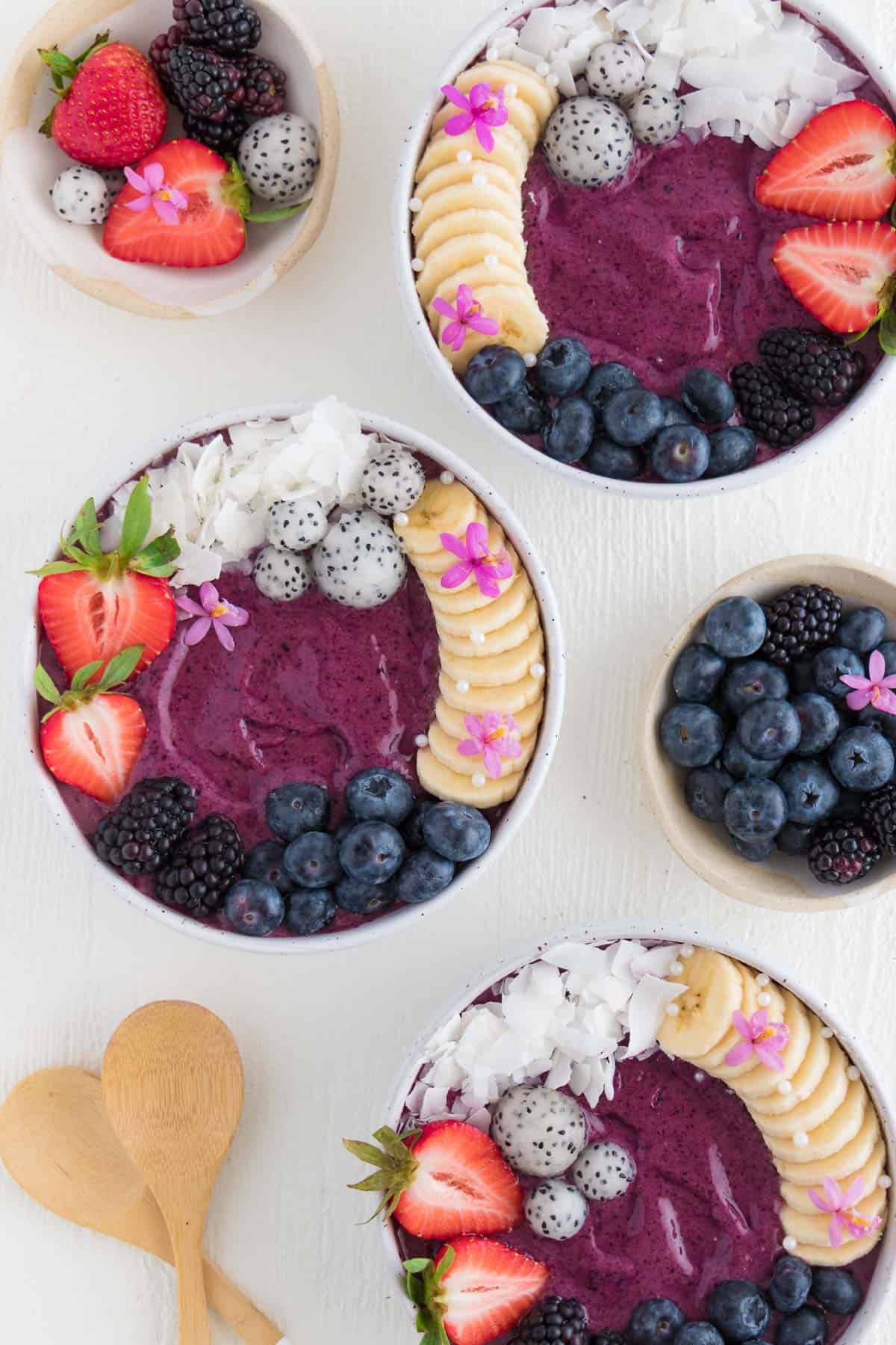 three berry acai bowls topped with fresh fruit