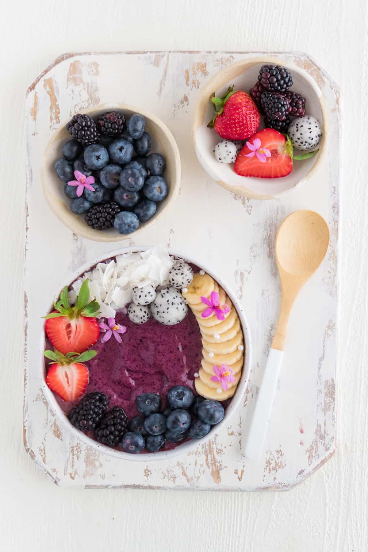 an acai smoothie bowl on top of a distressed white cutting board