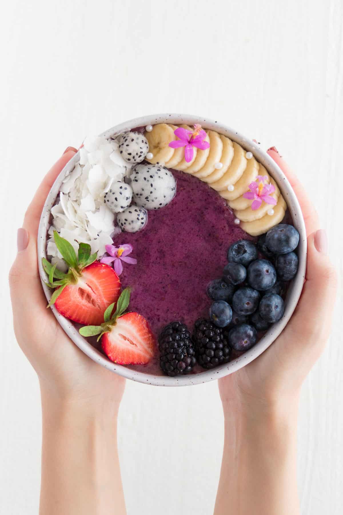 two hands holding an acai bowl