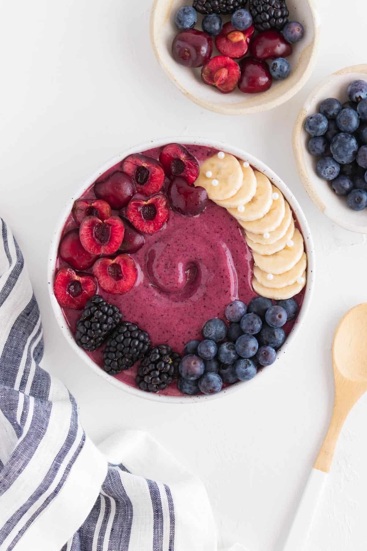 smoothie bowl topped with blueberries, cherries, blackberries, and banana