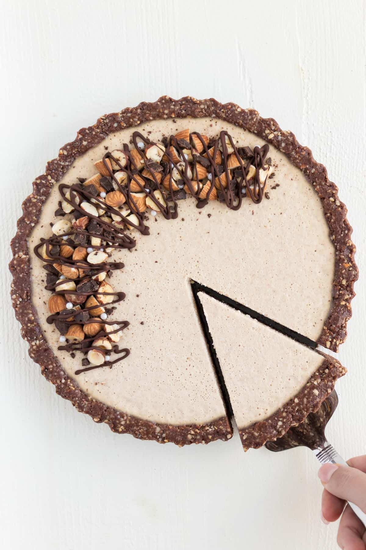 cutting a slice into vegan chocolate almond cheesecake
