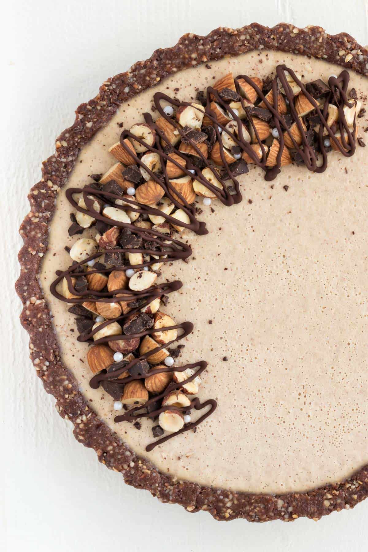 close up no bake cheesecake topped with chocolate, almonds, and hazelnuts