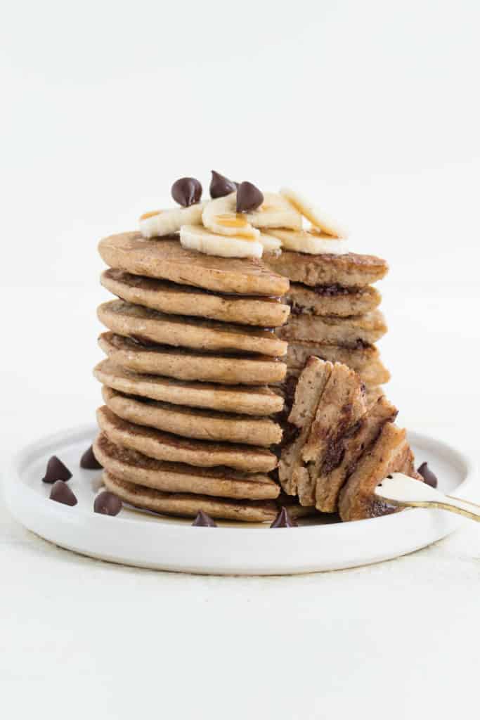 a fork cutting into a stack of vegan banana pancakes