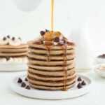 maple syrup poured over a stack of chocolate chip banana pancakes