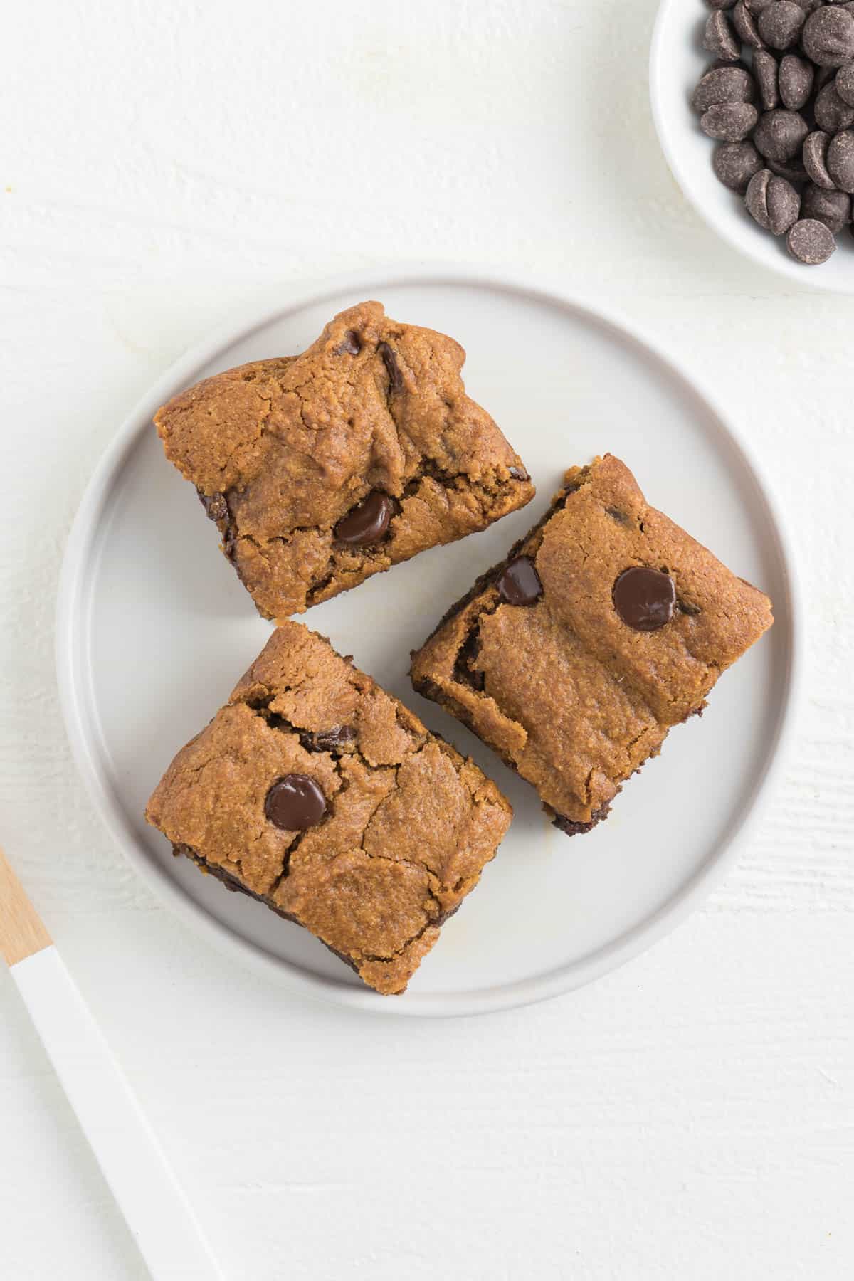 three pumpkin bars on top of a small white plate with chocolate chips