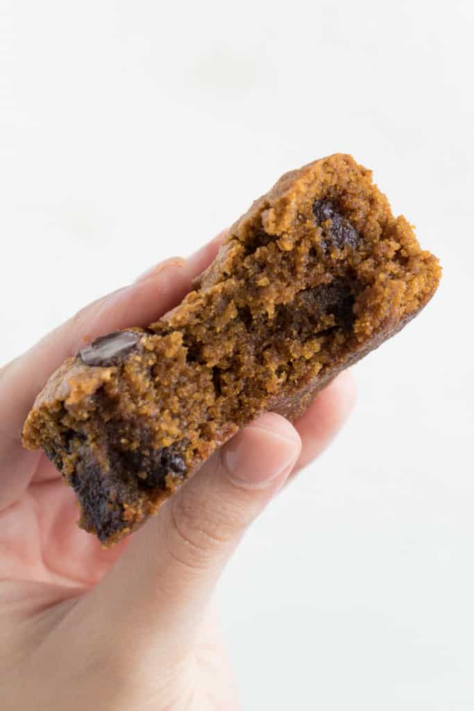 a hand holding a chocolate chip pumpkin blondie with a bite taken out of it