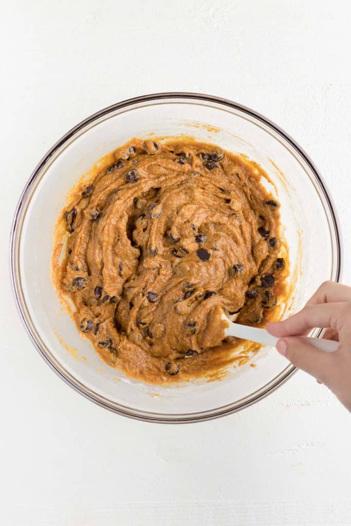 mixing together chocolate chip pumpkin bar batter in a glass bowl