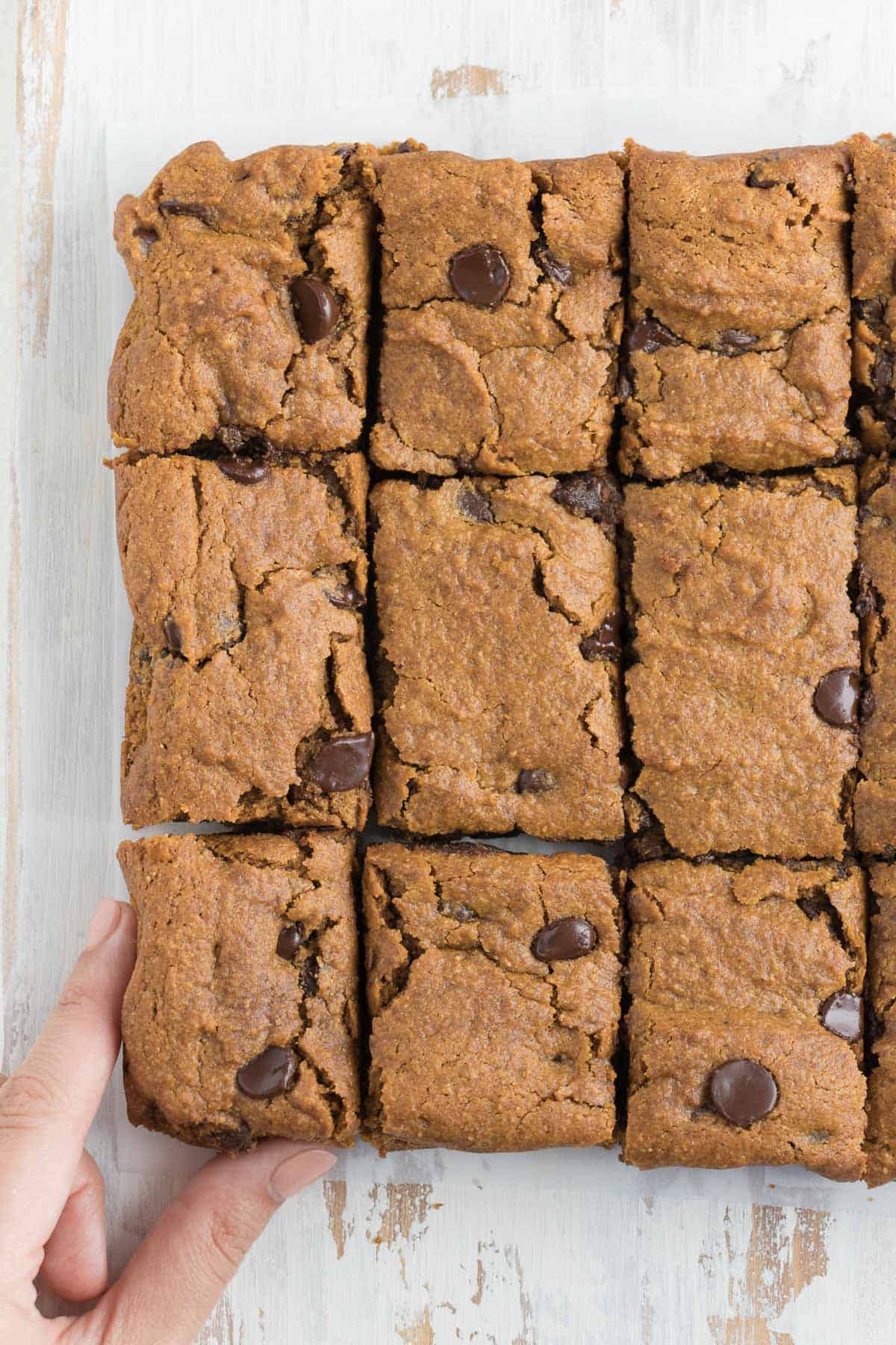 sliced chocolate chip pumpkin bars on top of a distressed white cutting board