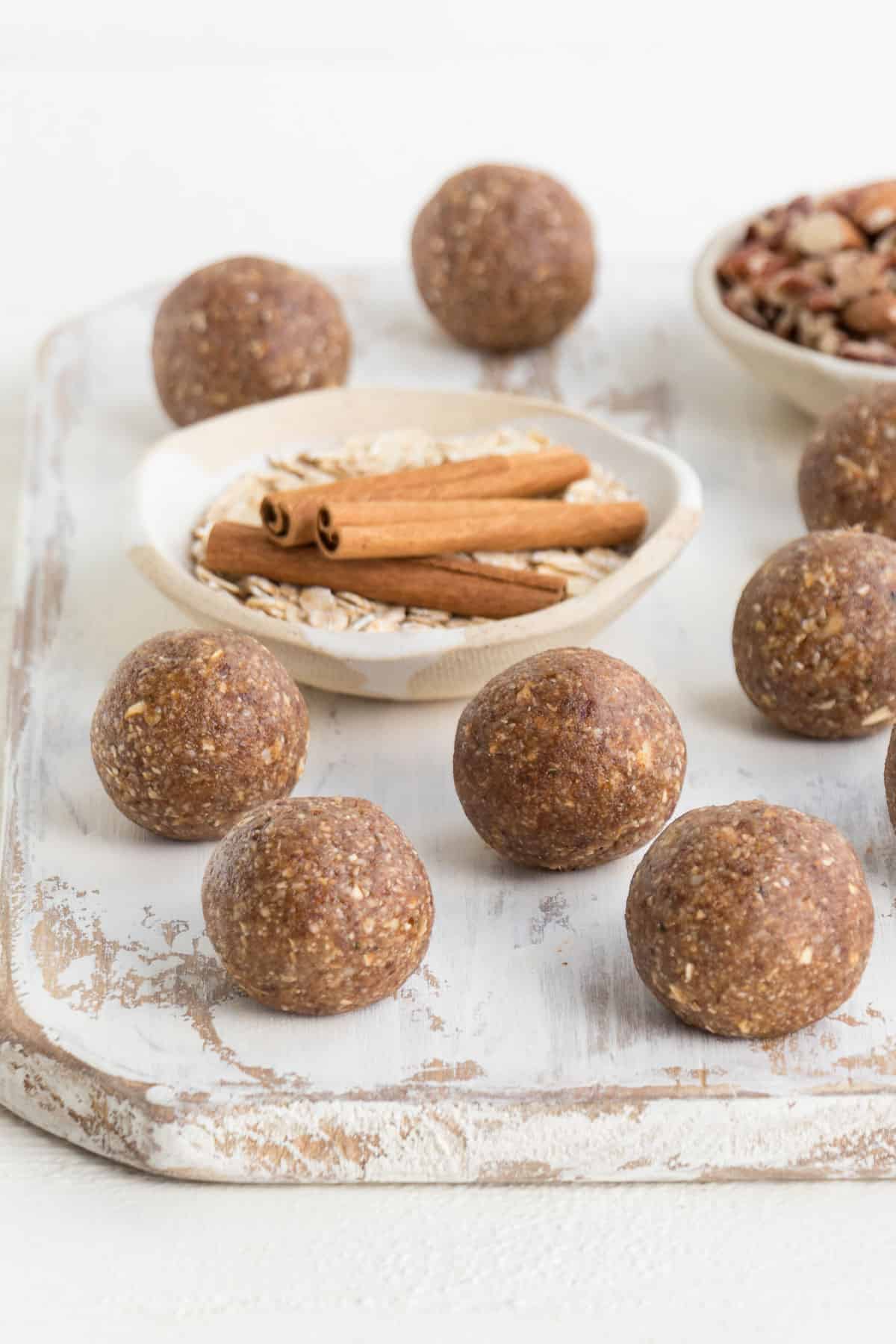 energy balls on a white distressed cutting board with cinnamon sticks