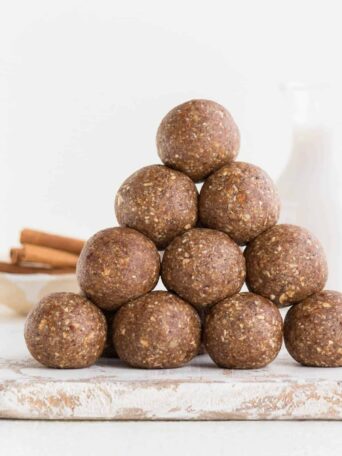 stack of pecan pie energy balls with cinnamon sticks and almond milk in the background