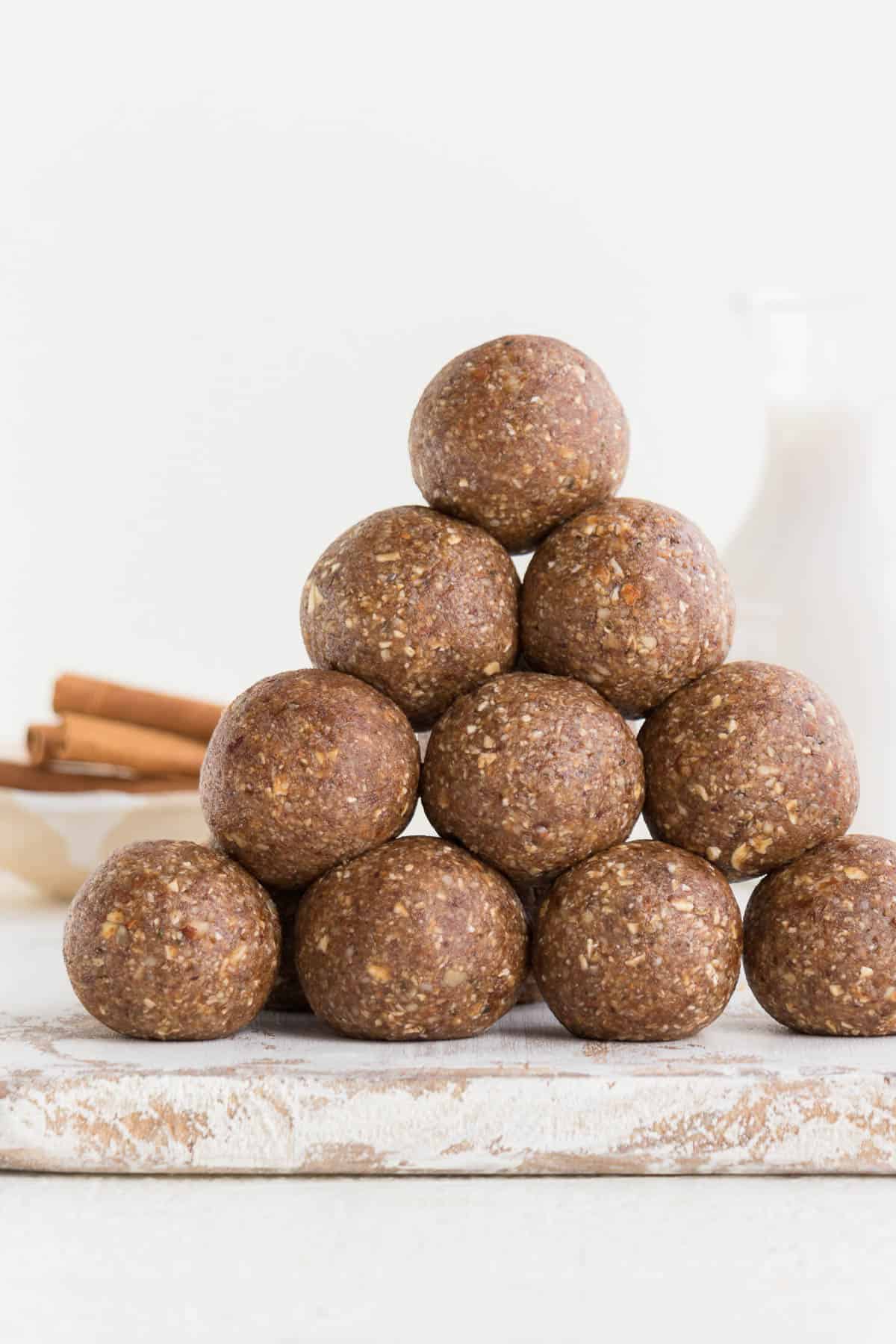 stack of pecan pie energy balls with cinnamon sticks and almond milk in the background