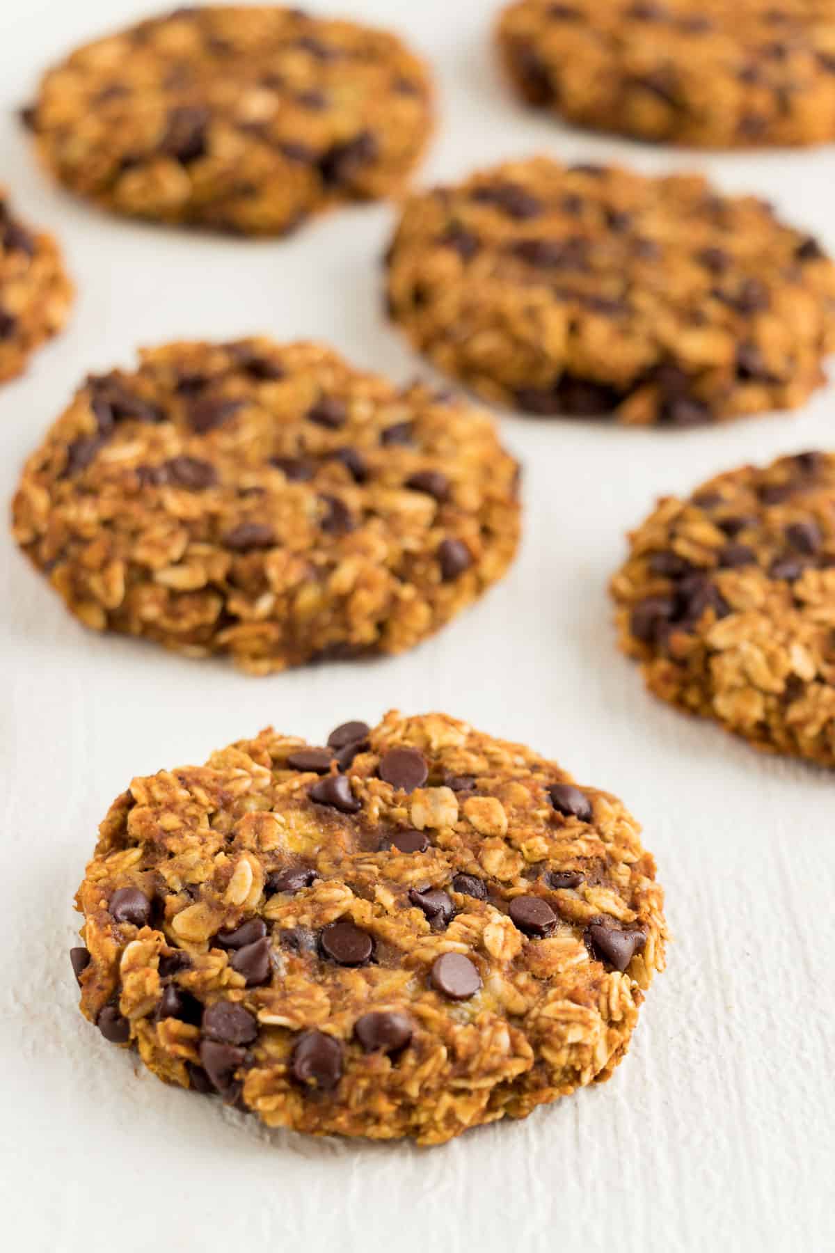 pumpkin chocolate chip oatmeal cookies on top of a white wooden board