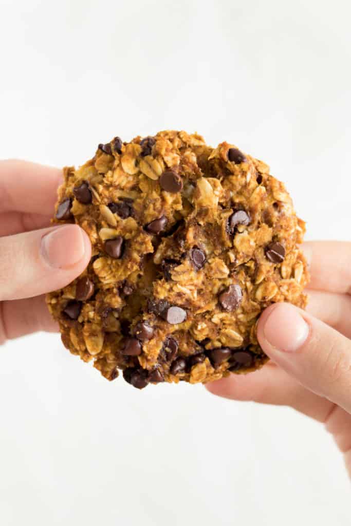 two hands pulling apart a freshly baked oatmeal cookie