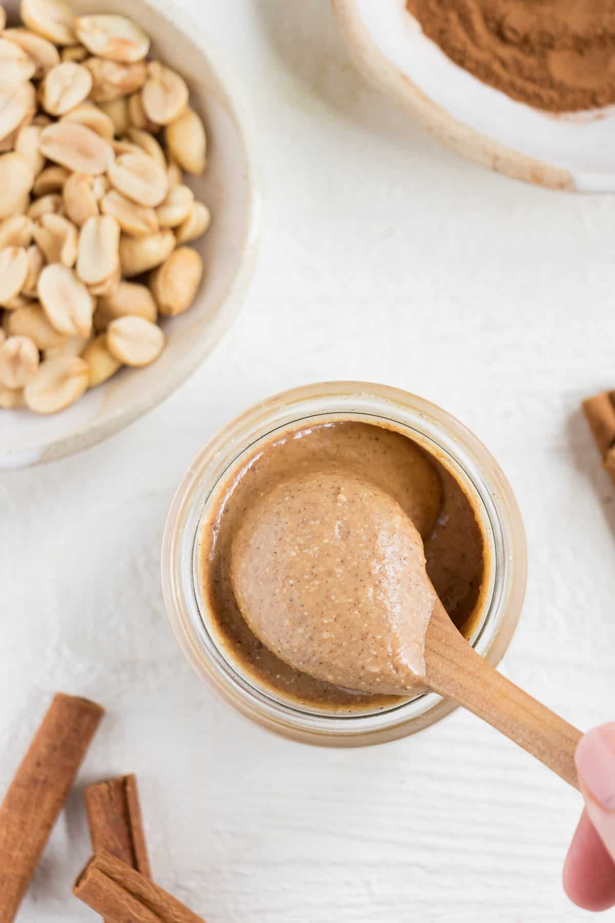 wooden spoon scooping nut butter out of a glass jar