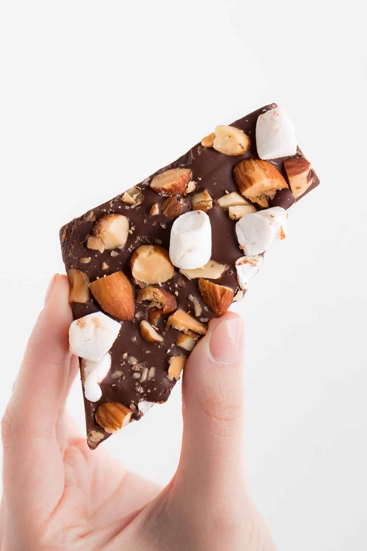 hand holding a piece of rocky road chocolate bark with marshmallows and almonds