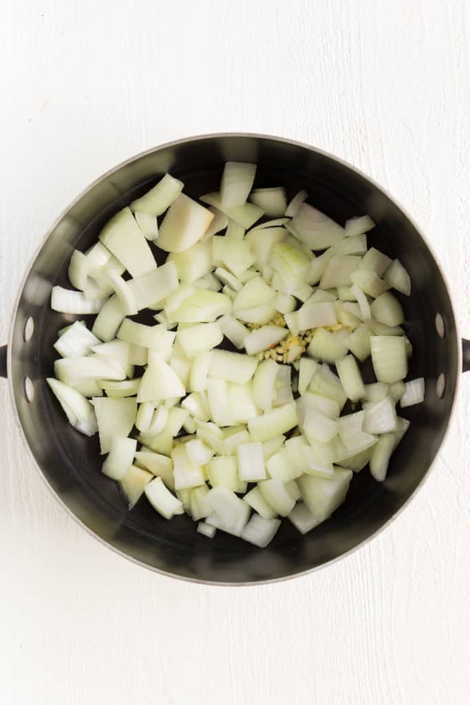 diced yellow onions and minced garlic inside a metal stock pot