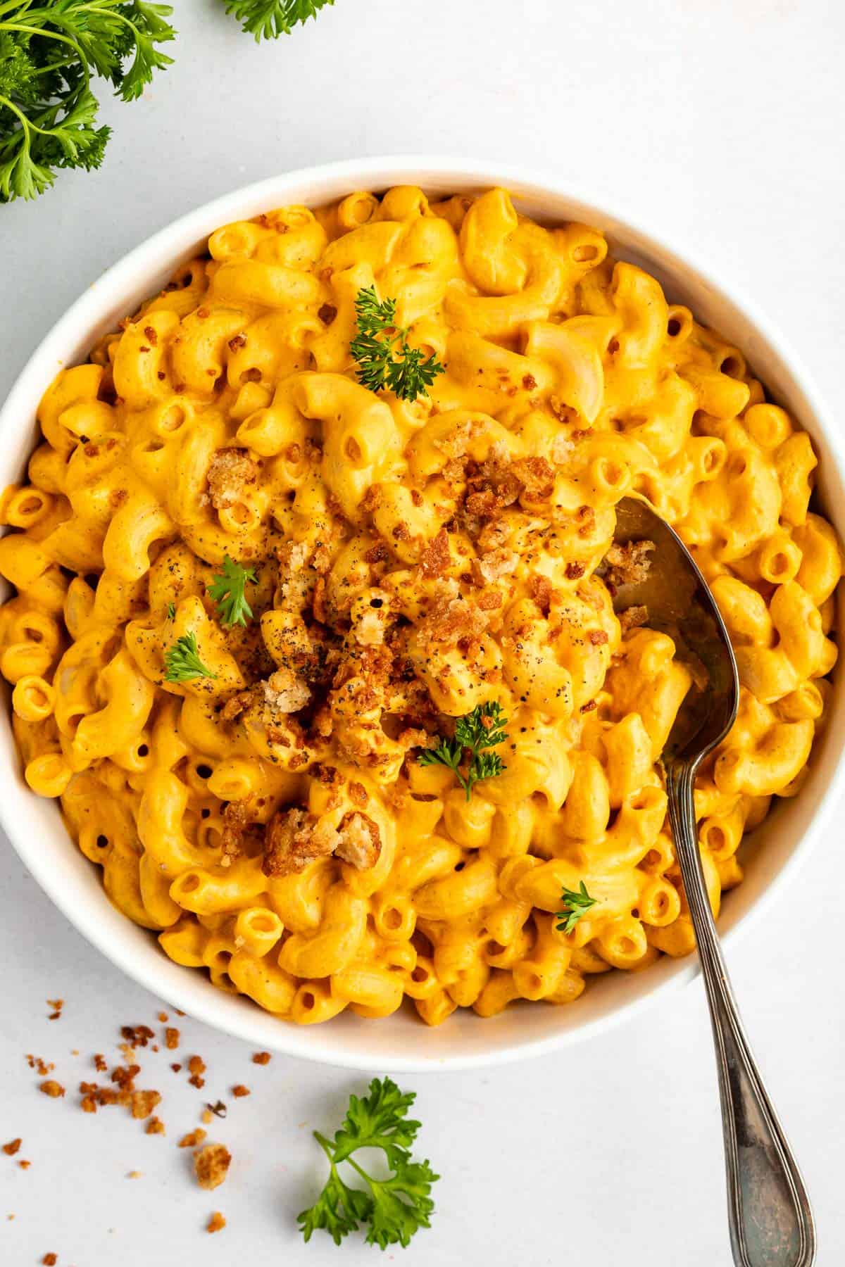 vegan mac and cheese inside a white bowl surrounded by a cream linen napkin