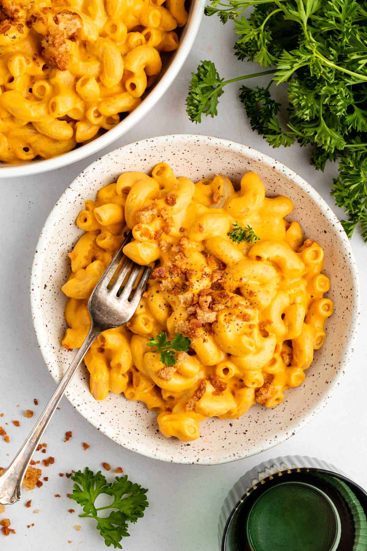 vegan sweet potato mac and cheese inside a speckled ceramic bowl with breadcrumbs and a fork