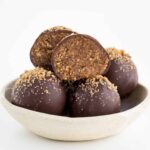 chocolate gingerbread truffles stacked inside a white and cream ceramic bowl