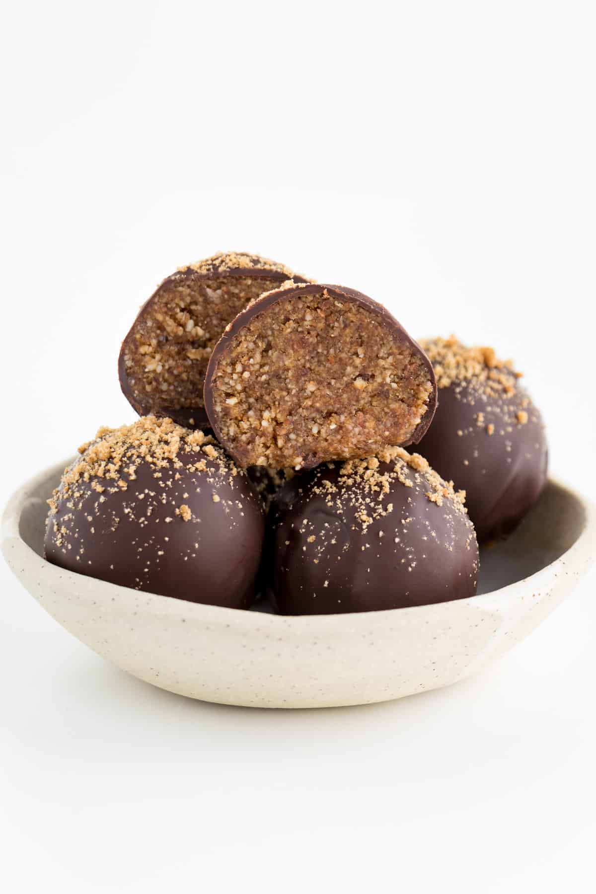 chocolate gingerbread truffles stacked inside a white and cream ceramic bowl