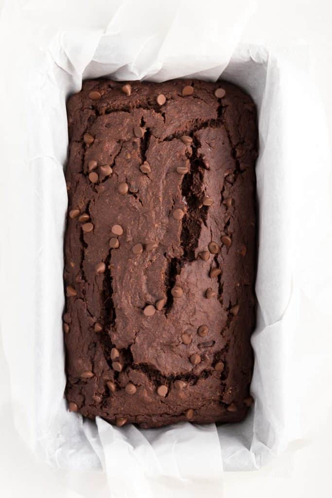 baked chocolate banana bread topped with chocolate chips inside a loaf pan