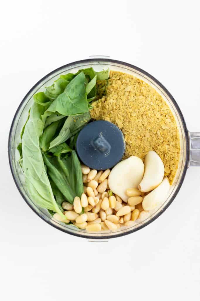 basil, nutritional yeast, garlic cloves, and pine nuts in a food processor