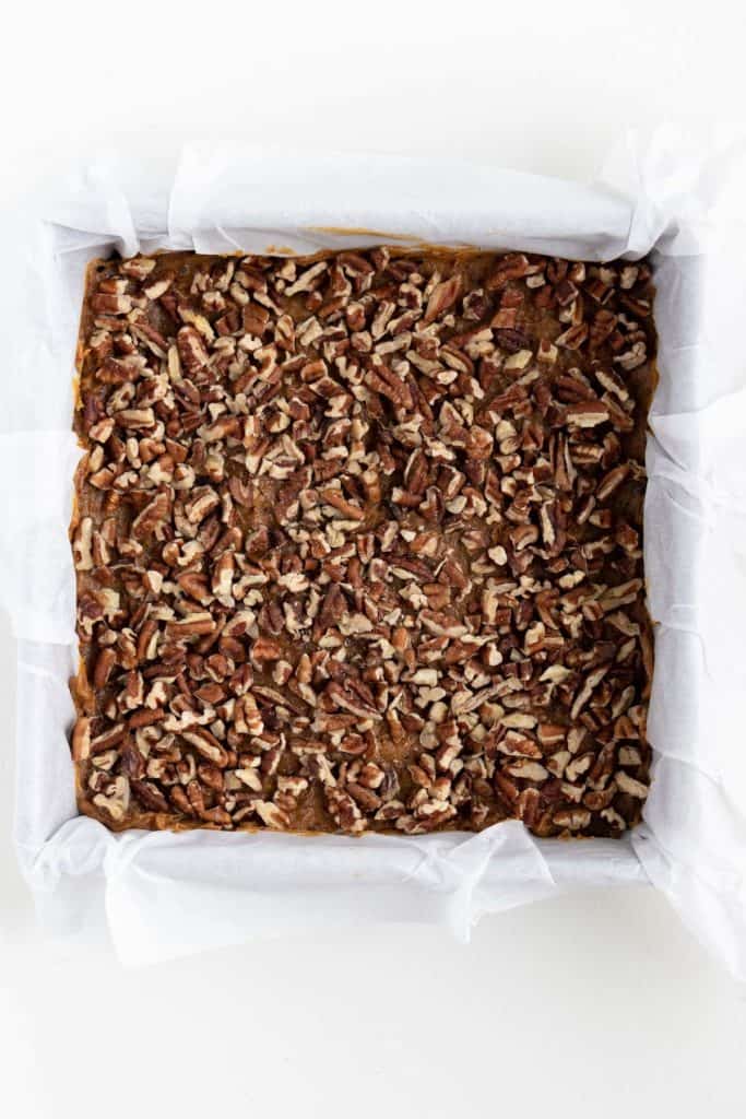 crushed pecans spread across the base of a square baking dish