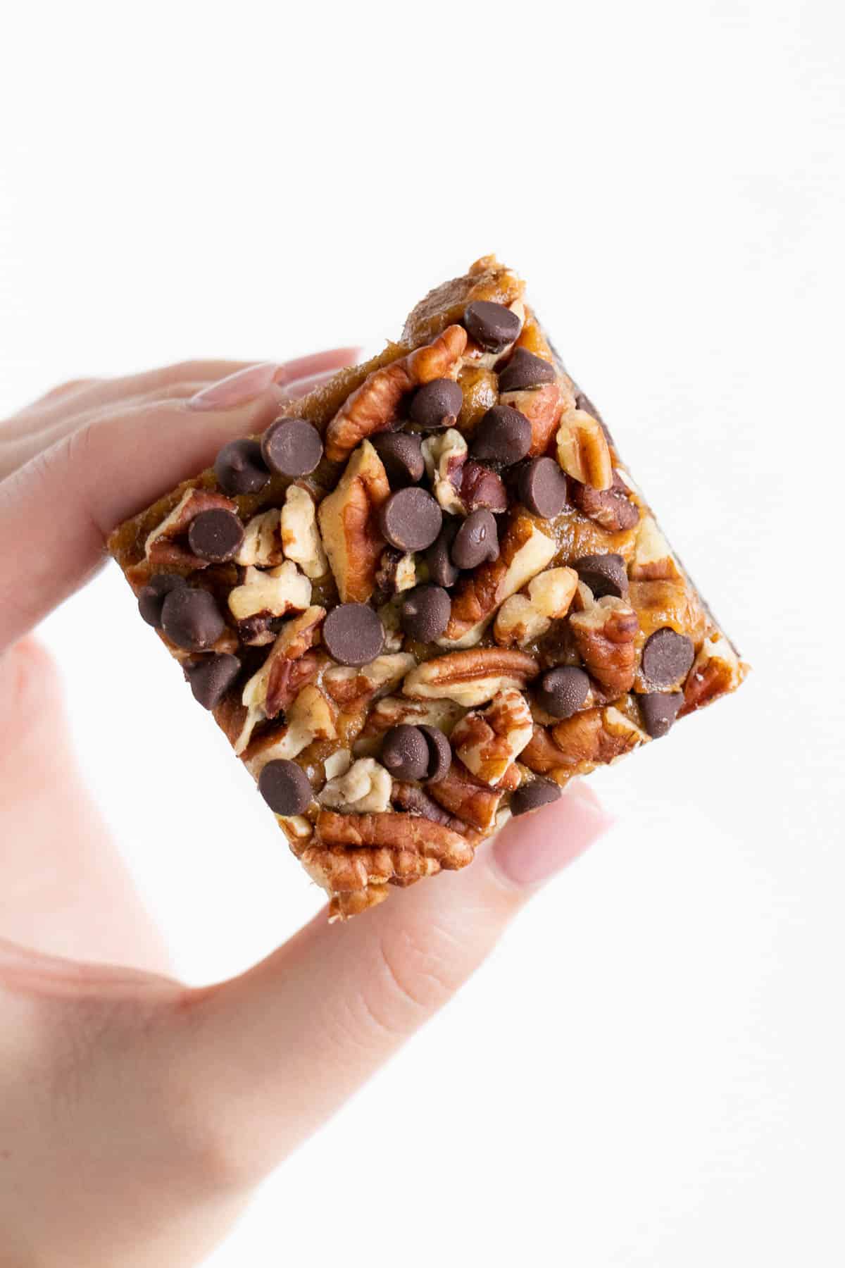 hand holding a no bake raw turtle brownie