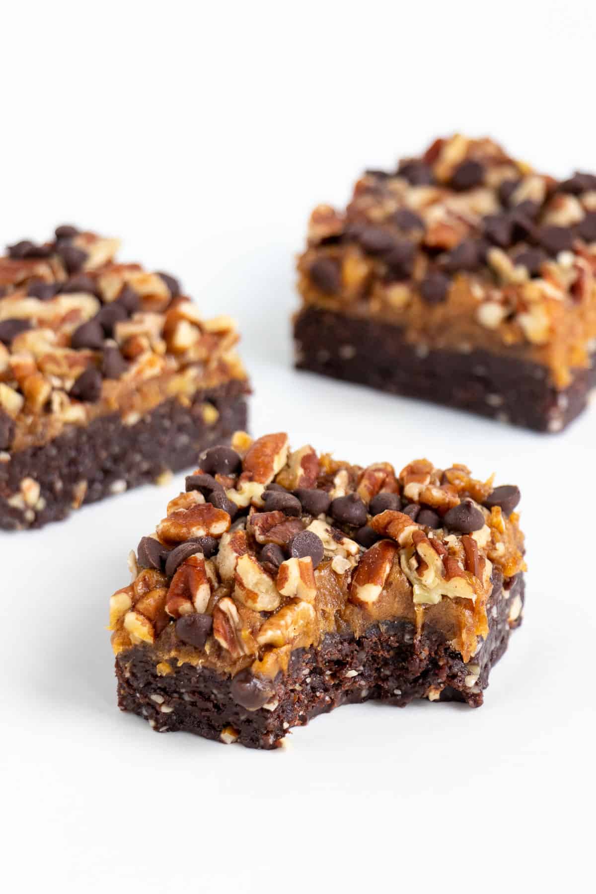 three no bake raw turtle brownies with a bite taken out of the center brownie