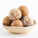 a stack of coconut almond bliss balls in a ceramic bowl