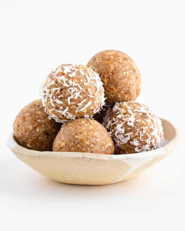 a stack of coconut almond bliss balls in a ceramic bowl