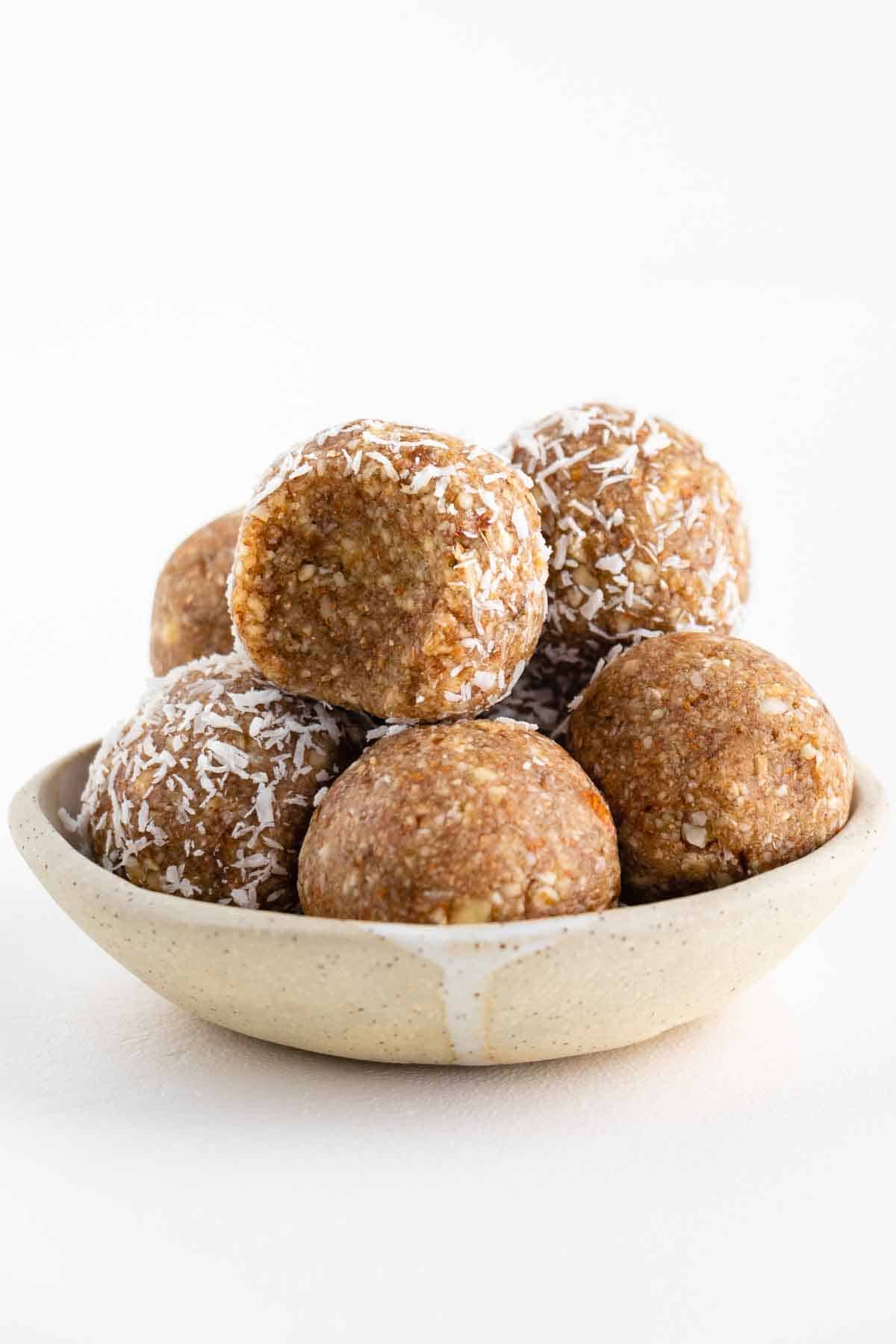 coconut almond bliss balls stacked in a ceramic bowl