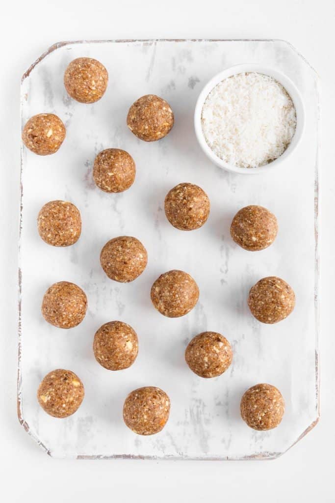 energy balls beside a small white bowl of shredded coconut