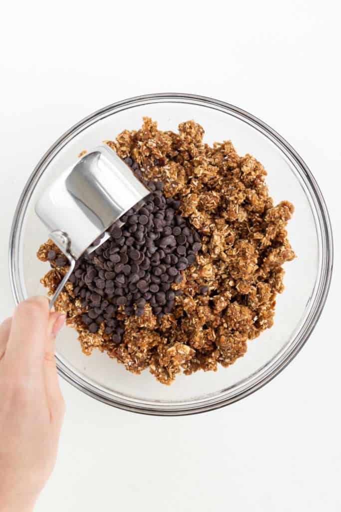 a metal measuring cup filled with chocolate chips being poured over a bowl