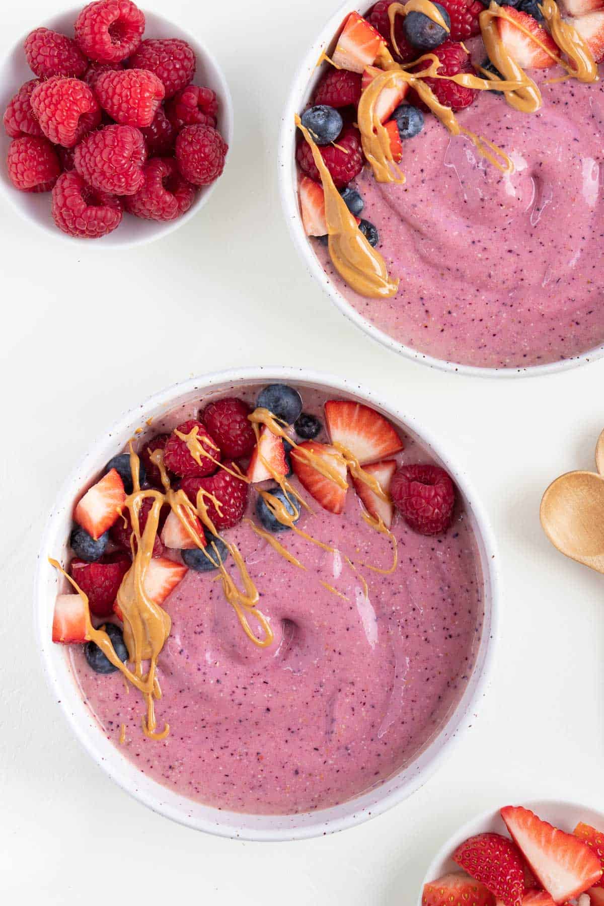 berry smoothie bowls topped with peanut butter, strawberries, raspberries, and blueberries