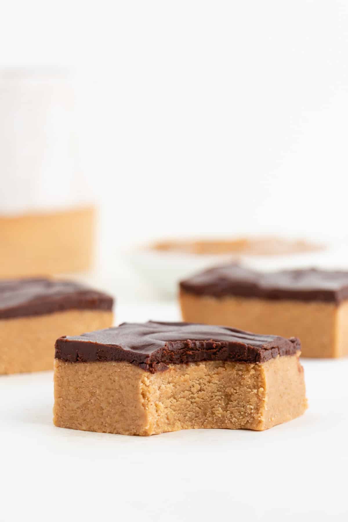 three no bake vegan chocolate peanut butter bars with a bite taken out of the center bar