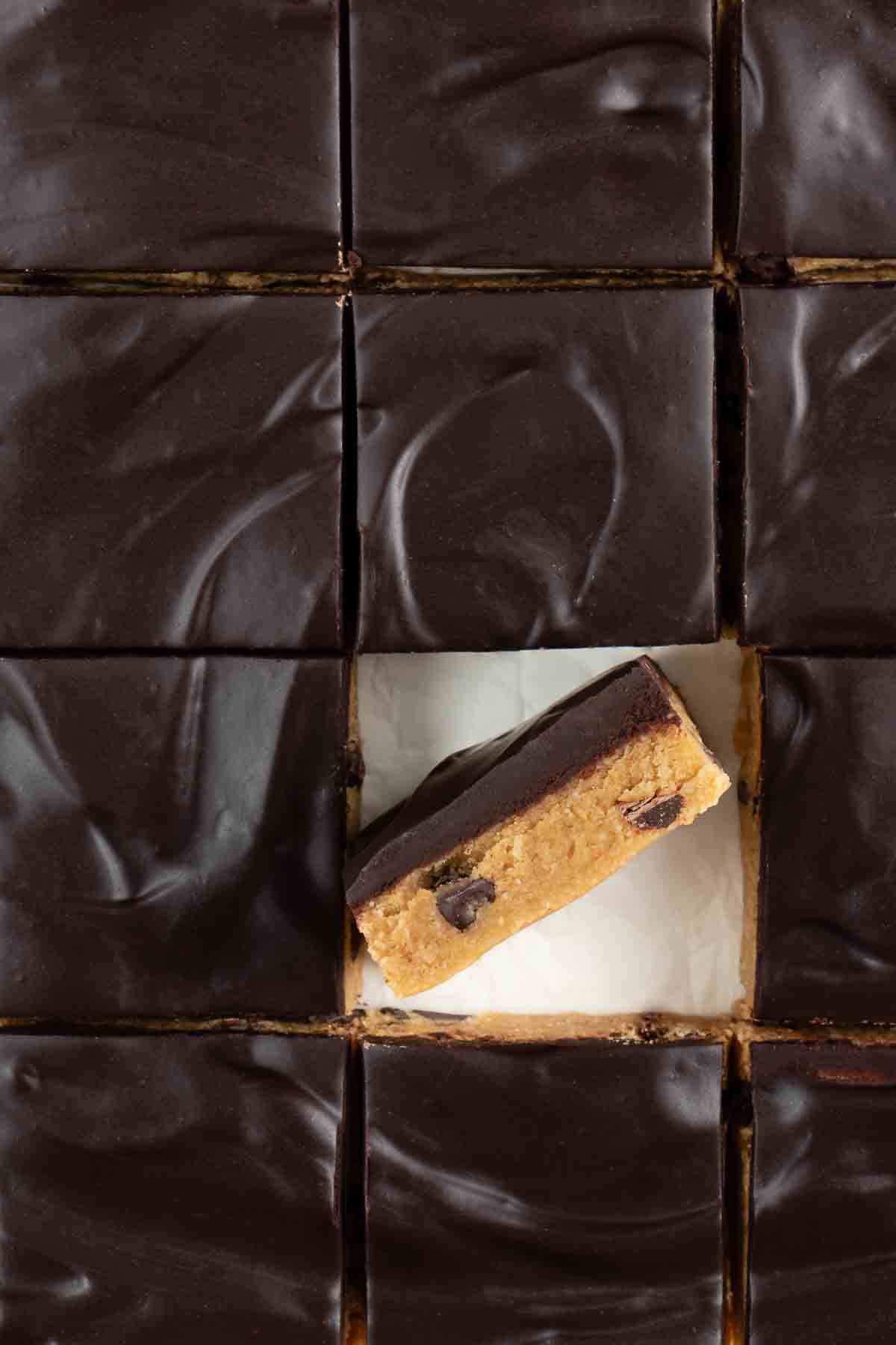 chocolate frosted no bake cookie dough bars sliced into squares with one bar on its side