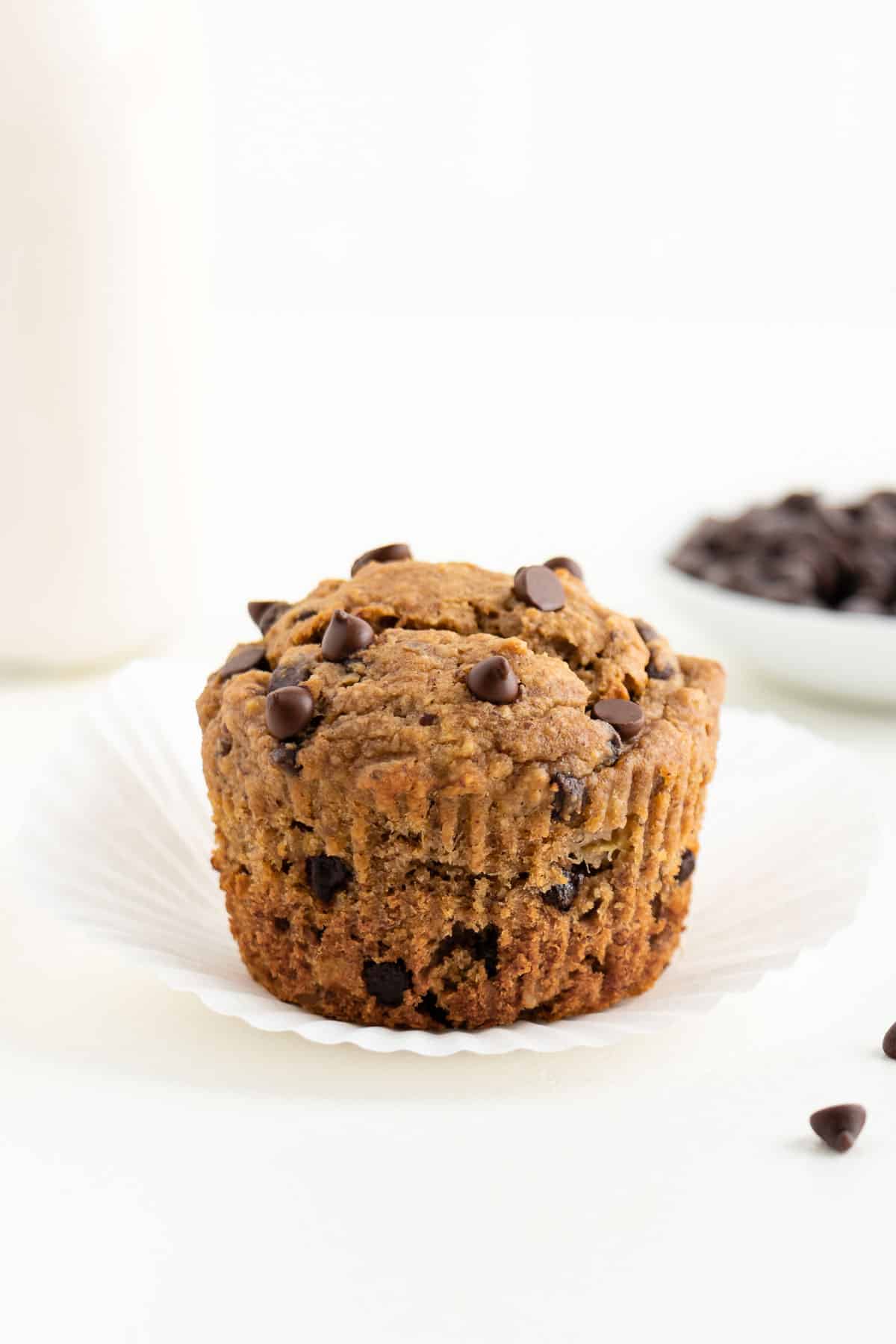 a chocolate chip banana muffin with the parchment paper liner remove