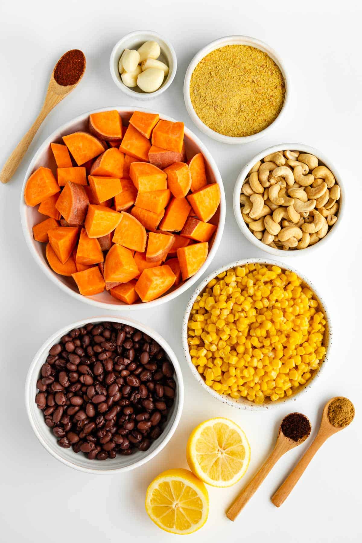 cubed potatoes, beans, cashews, corn, lemon juice, garlic, spices, and diced onion in white bowls