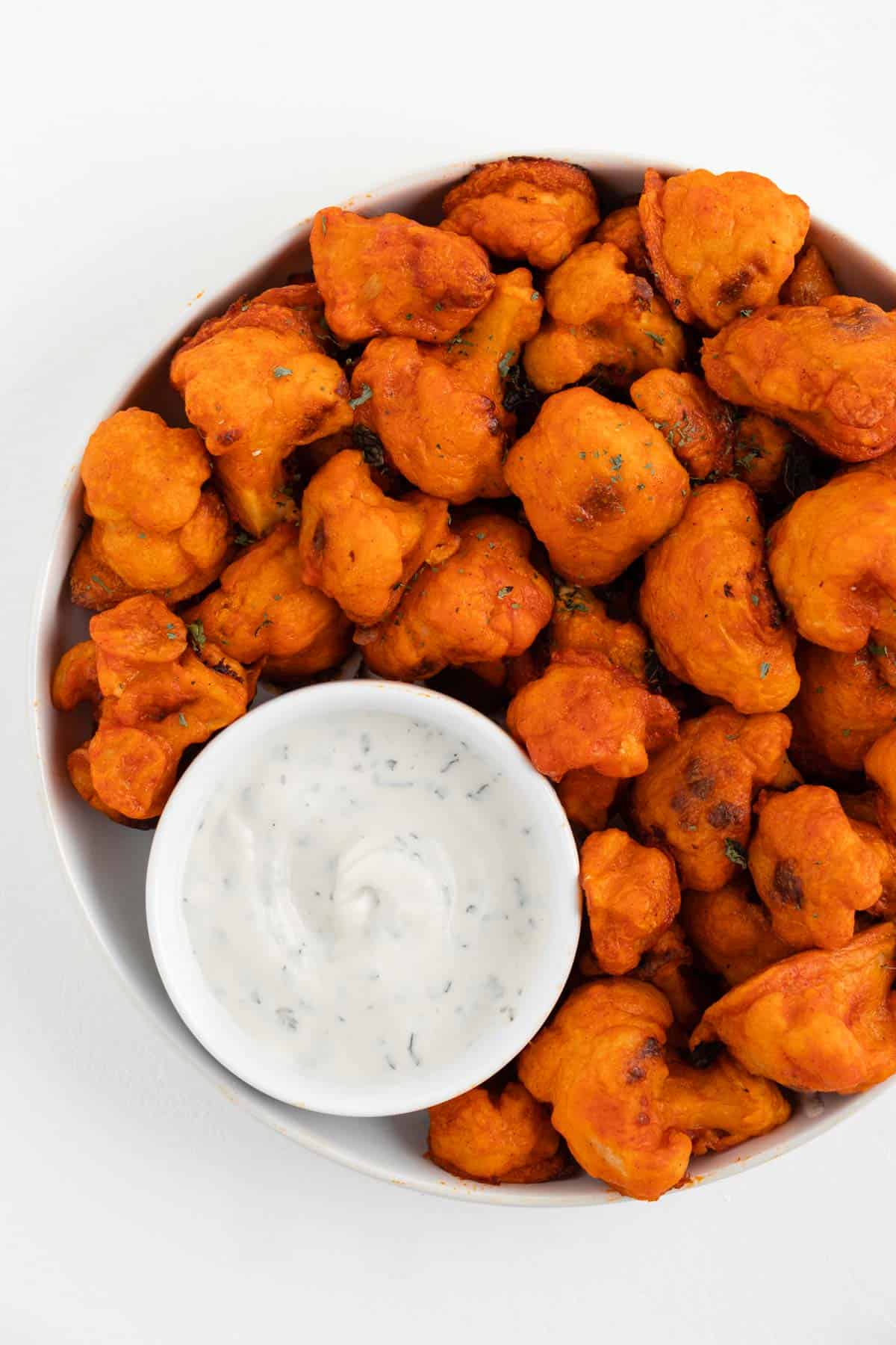 vegan buffalo cauliflower wings with dairy-free ranch dressing dip in a bowl