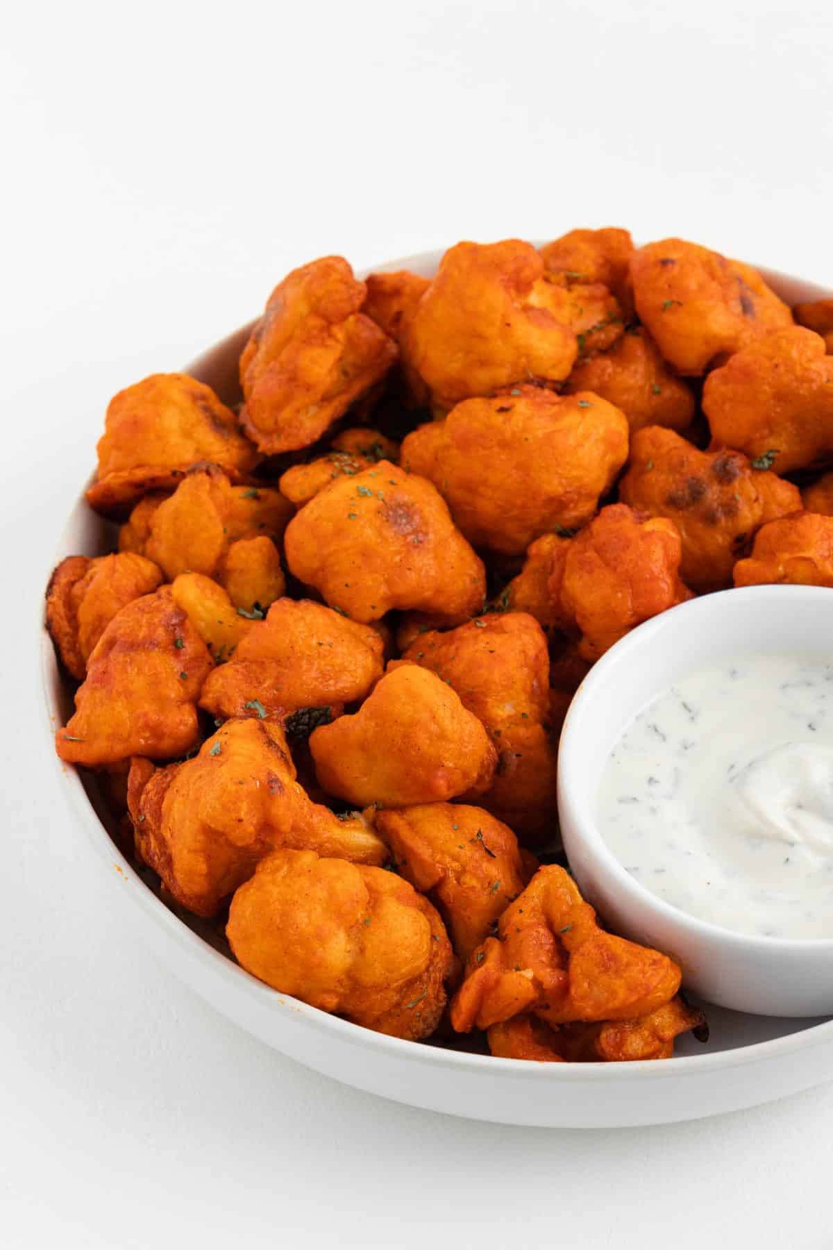 vegan buffalo cauliflower wings with dairy-free ranch dressing dip in a bowl