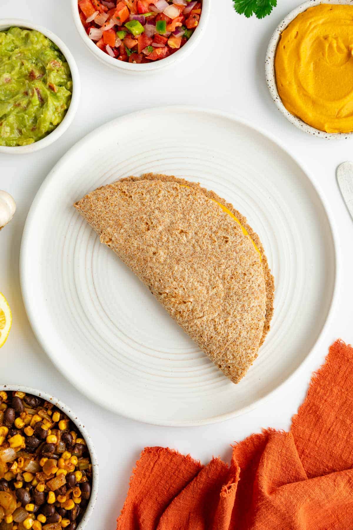 a folded tortilla stuffed with black beans, corn, and sweet potato on a white plate