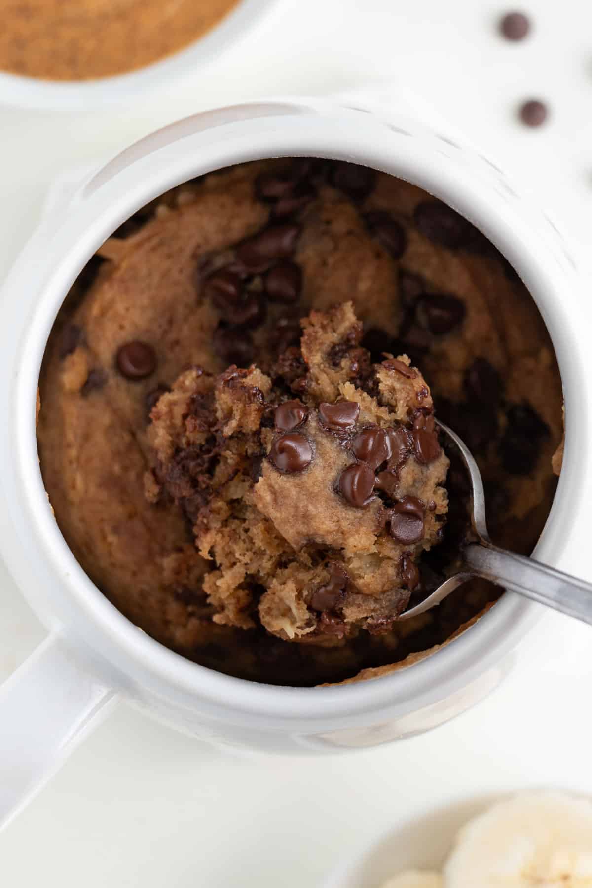 a spoon scooping into a vegan chocolate chip banana mug cake