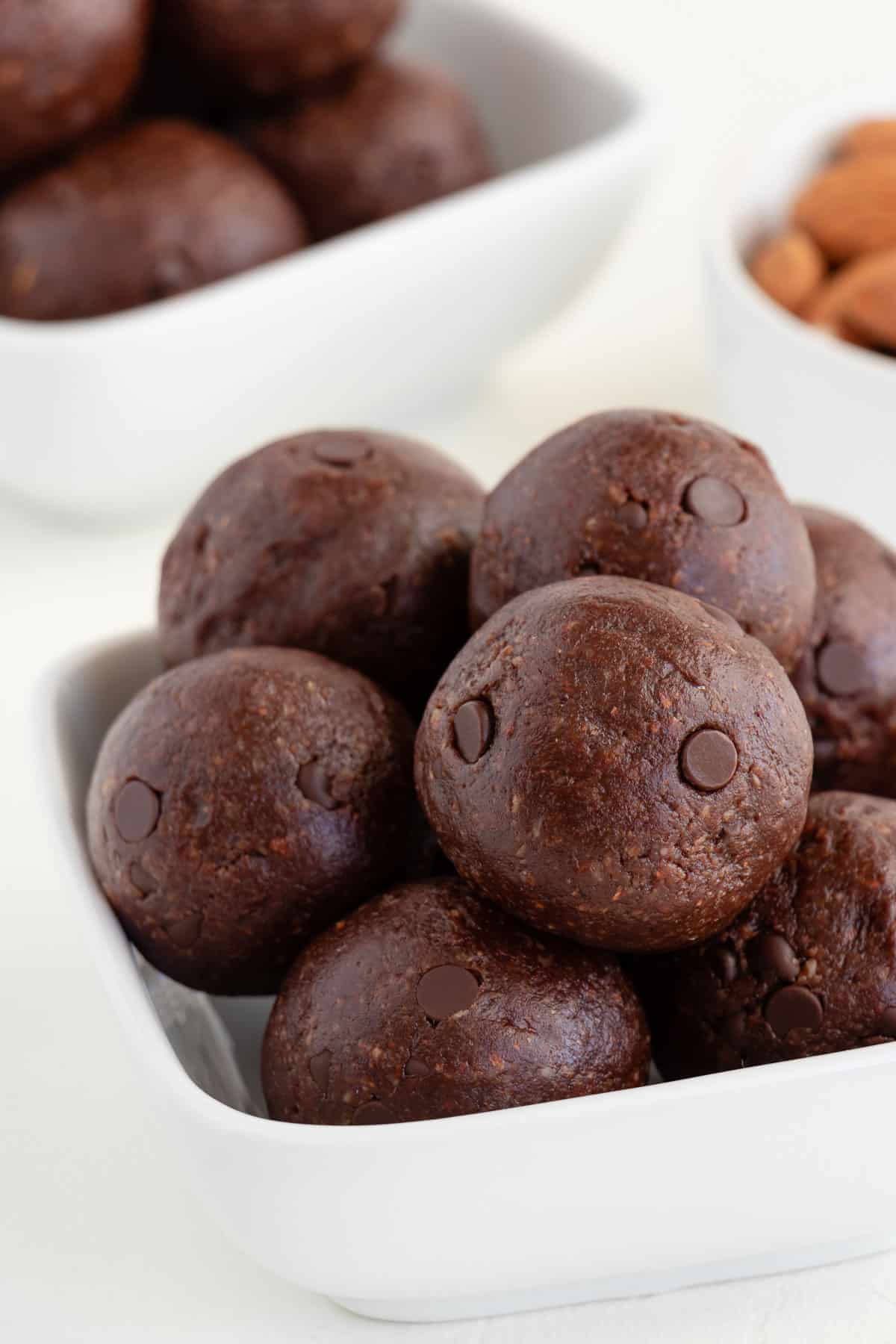 no bake brownie bliss balls stacked inside a square white bowl