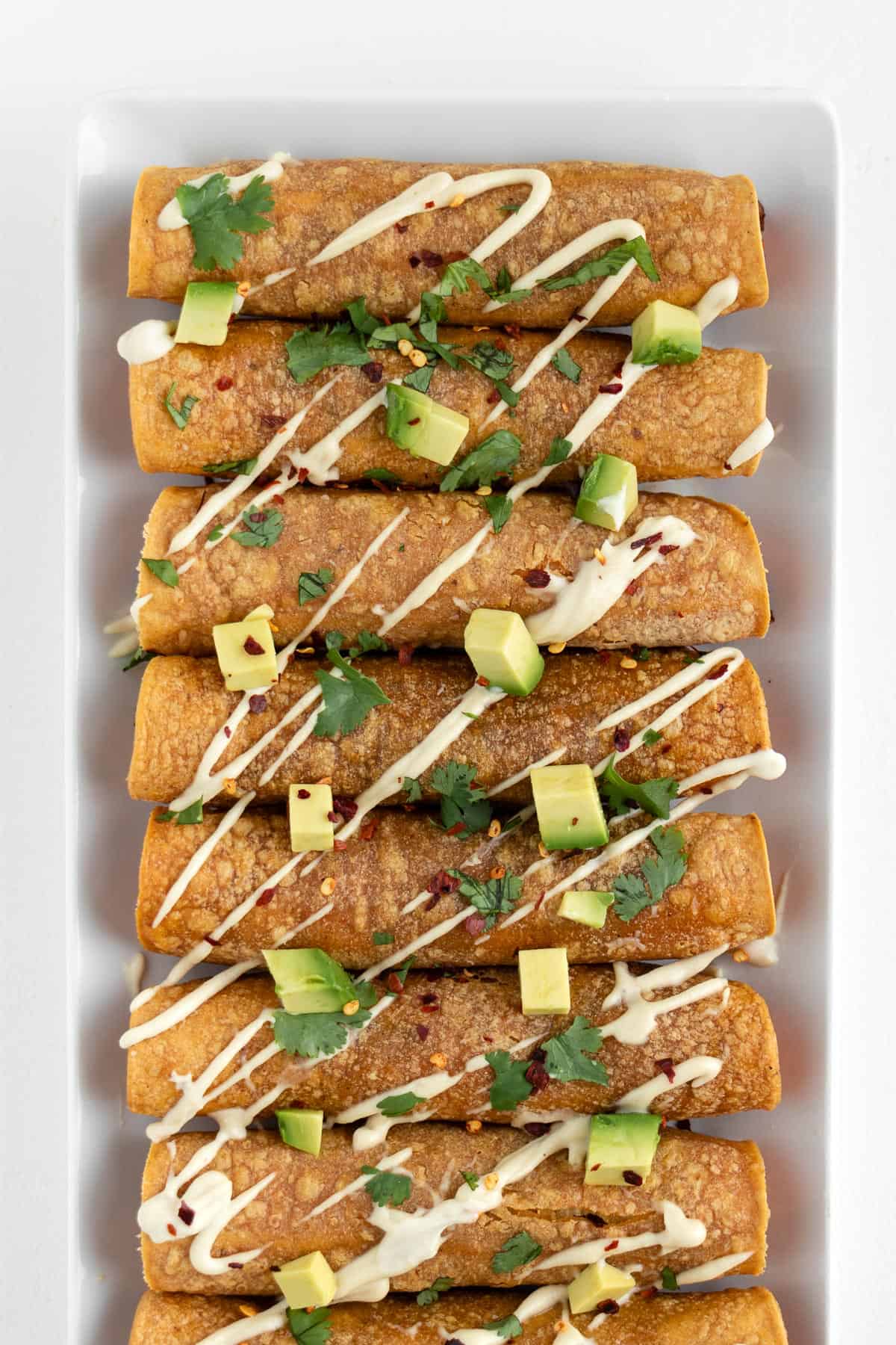 vegan sweet potato black bean taquitos on a white plate