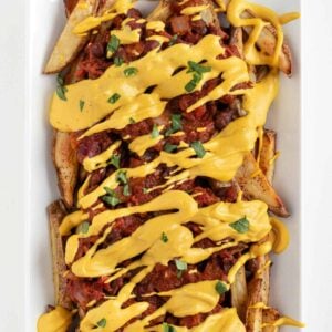 vegan chili cheese fries on a white rectangular plate